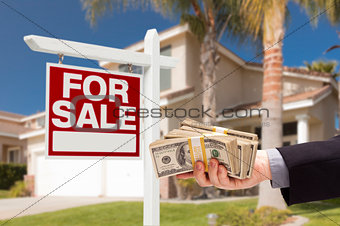 Buyer Handing Over Cash for House with For Sale Sign