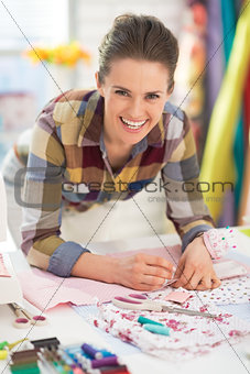 Portrait of happy seamstress working in studio