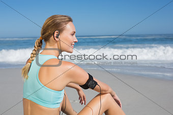 Fit woman sitting on the beach taking a break smiling