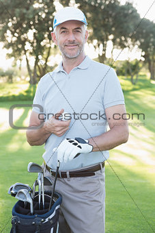 Handsome golfer standing with golf bag