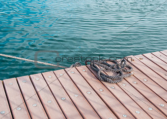 Coiled marine rope on wooden pier