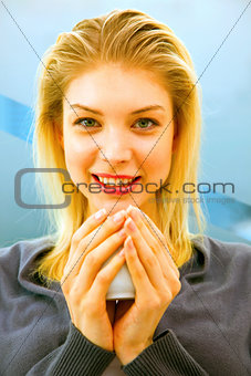 Close-up of smiling young woman holding cup