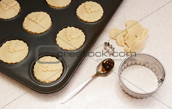 Uncooked mince pies in a bun tin
