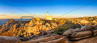 Rocky ocean coastline panorama with lighthouse at sunset