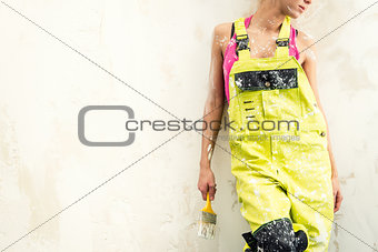 Female in coverall holding paint brush and hardhat
