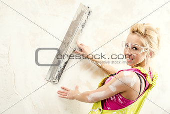 Female with putty knife working indoors