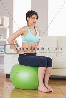 Fit brunette sitting on exercise ball