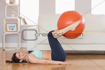 Fit brunette lifting exercise ball with legs