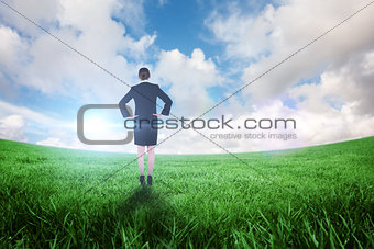 Composite image of young businesswoman standing with hands on hips