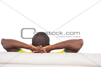 Man sitting on sofa with hands behind head