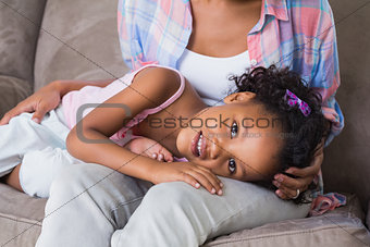 Cute daughter lying across mothers lap