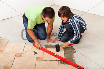 Man and boy laying ceramic floor tiles