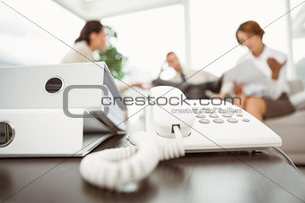 Executives with land line phone and folders in foreground