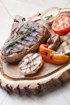 Portion of BBQ t-bone steak with  sauce  and grilled vegetables