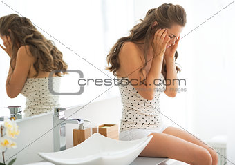 Stressed young woman sitting in bathroom