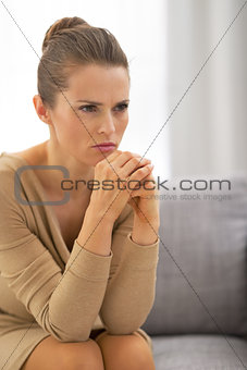 Concerned young housewife sitting in living room