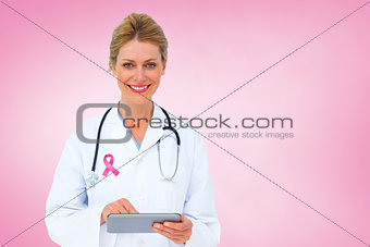 Composite image of blonde doctor using tablet pc
