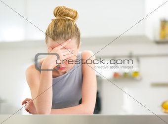 Portrait of stressed young housewife in kitchen