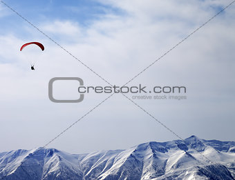 Paraglider silhouette of mountains in sunlight sky