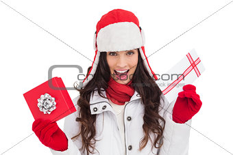Excited brunette in winter clothes holding gifts