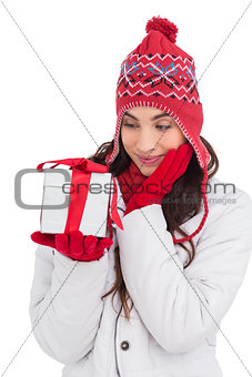 Content brunette in winter clothes holding gift