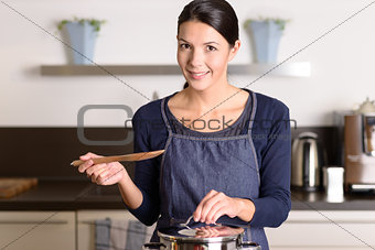 Young woman cooking over the stove