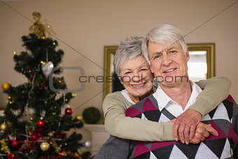 Senior couple smiling beside their christmas tree