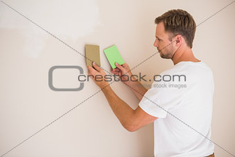 Handsome decorator sanding down the wall