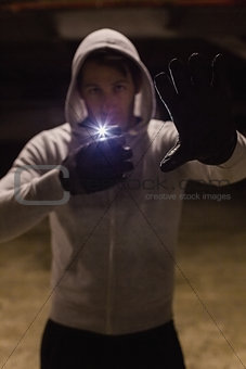 Man in hood jacket standing while making light with his phone