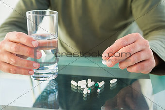 Close up of a man holding pill and glass of water