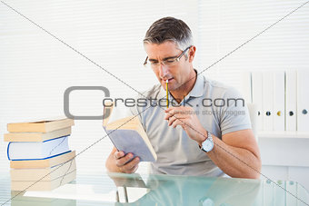 Man with glasses thinking and reading a book