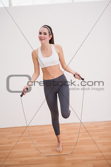 Fit brunette using skipping rope