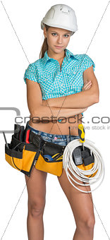 Serious electrician in helmet, shorts, shirt, tool belt with tools