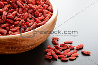 Wooden Bowl Full of Dried Goji Berries on the Dark Table