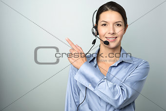 Smiling businesswoman with a headset pointing