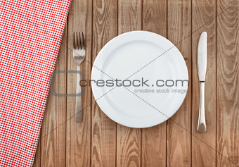 white plate and fork on old wooden table with red cloth