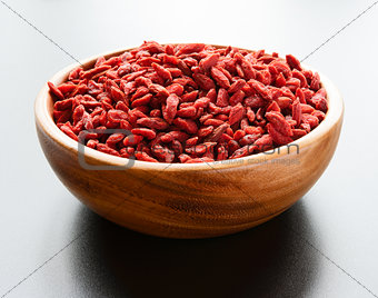 Wooden Bowl Full of Dried Goji Berries on the Dark Table