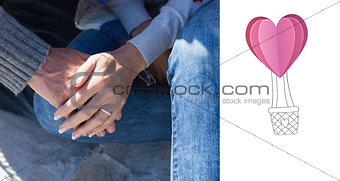 Composite image of couple holding hands sitting on sand