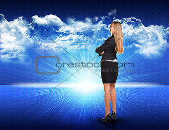 Businesswoman standing against blue landscape with rising sun