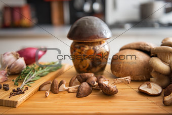 Closeup on jar of pickled mushroom on cutting board
