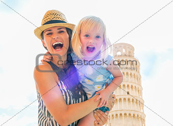 Portrait of smiling mother and baby girl in front of leaning tow