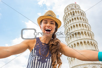 Portrait of young woman making selfie in front of leaning tower 