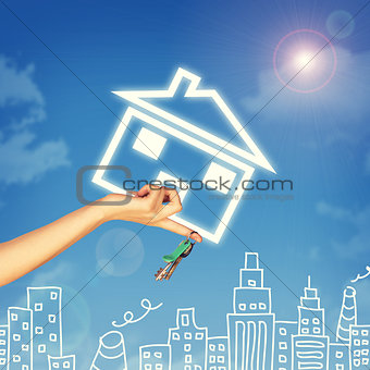 Hand holding house icon and key. Background of sky, clouds, sun