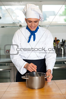Young male chef with whisk and mixing bowl