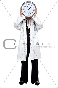 Lady doctor holding clock before her face