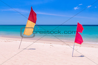Red and yellow-red flags on the empty beach