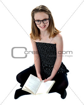 School girl sitting on floor holding book