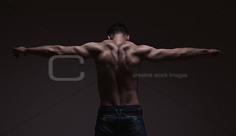 strong athletic mans back on dark background