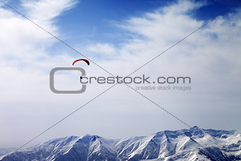 Paraglider silhouette of mountains in windy sky