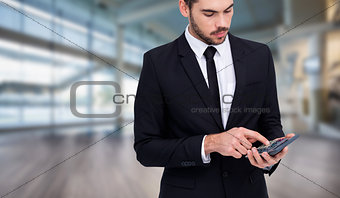 Composite image of concentrated businessman in suit using calculator